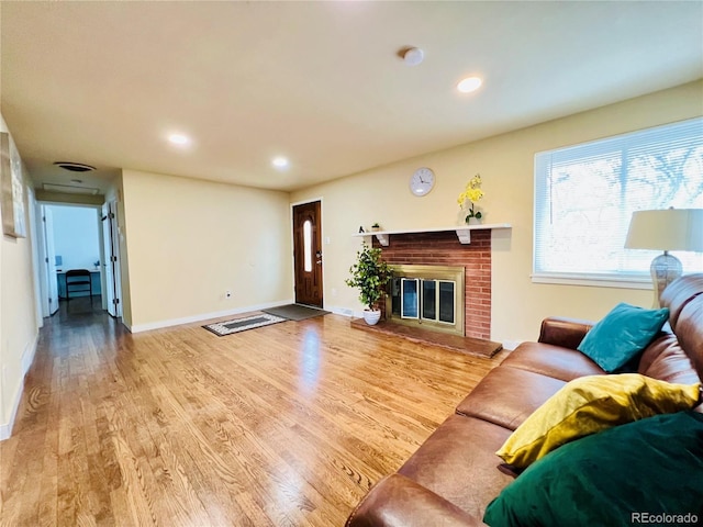 living room featuring recessed lighting, a brick fireplace, light wood-style flooring, and baseboards