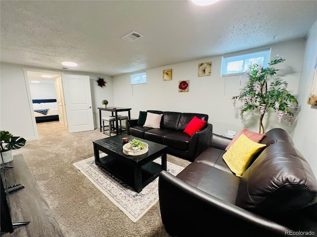 living area with a textured ceiling, light carpet, and visible vents