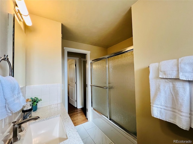 bathroom with a shower stall, vanity, and decorative backsplash