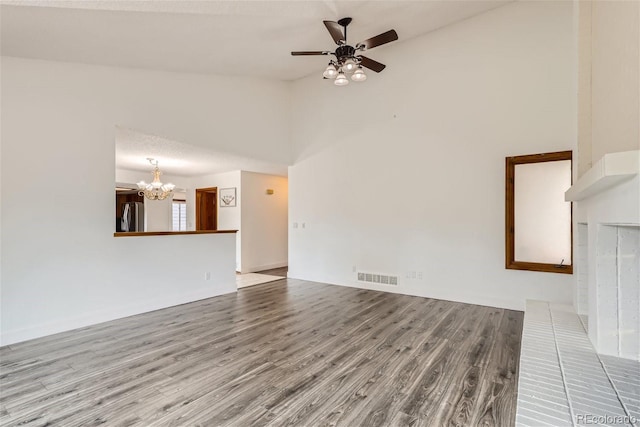 unfurnished living room with high vaulted ceiling, visible vents, wood finished floors, and ceiling fan with notable chandelier