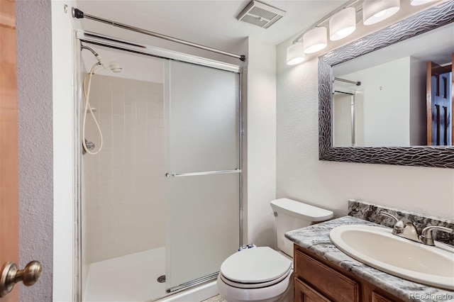 bathroom featuring visible vents, a textured wall, toilet, a stall shower, and vanity