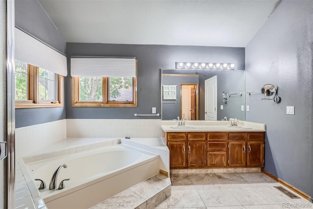 bathroom with a bath, double vanity, a sink, and visible vents