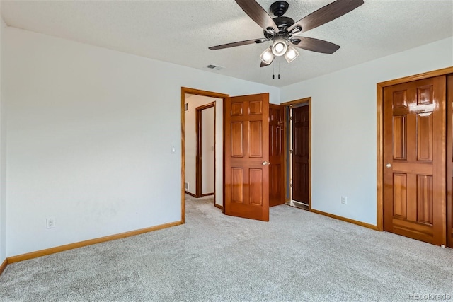 unfurnished bedroom featuring baseboards, a textured ceiling, and light colored carpet