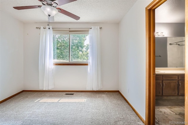 spare room featuring carpet floors, visible vents, a textured ceiling, and baseboards