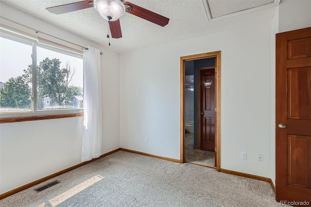 unfurnished room featuring visible vents, a ceiling fan, carpet flooring, a textured ceiling, and baseboards