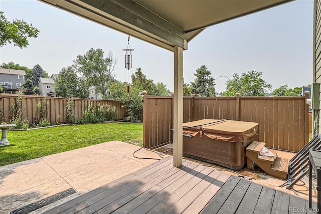 deck featuring a patio area, a hot tub, a fenced backyard, and a yard