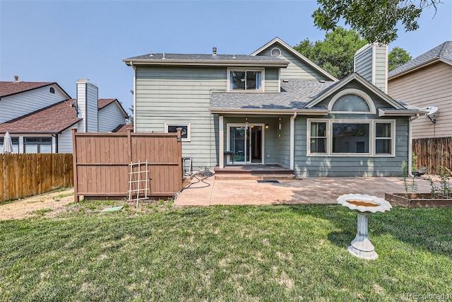 back of property with a lawn, a chimney, roof with shingles, fence, and a patio area