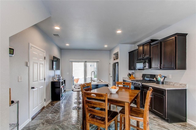 kitchen with black appliances, dark brown cabinetry, and sink