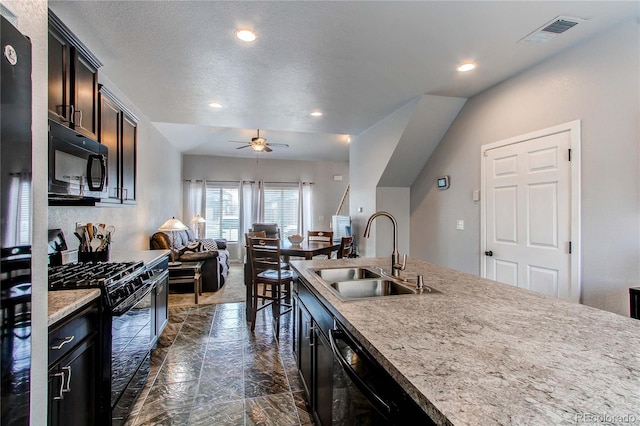 kitchen with light stone countertops, a textured ceiling, ceiling fan, sink, and black appliances