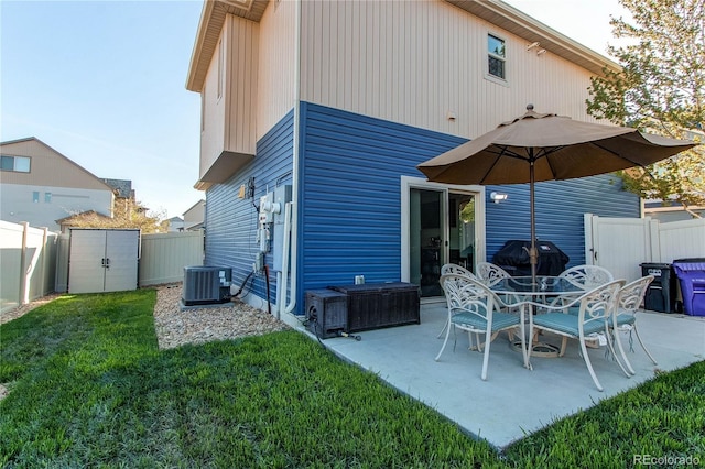 back of house featuring central AC, a lawn, a fenced backyard, and a storage unit