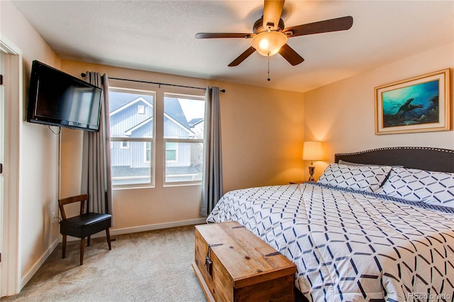 bedroom featuring light colored carpet, baseboards, and a ceiling fan