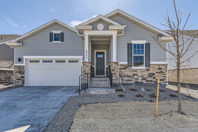 view of front of home with stone siding, an attached garage, and driveway