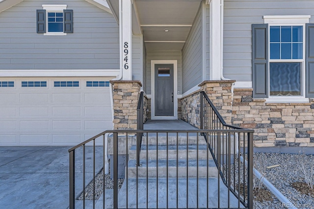 property entrance featuring stone siding, concrete driveway, and a garage