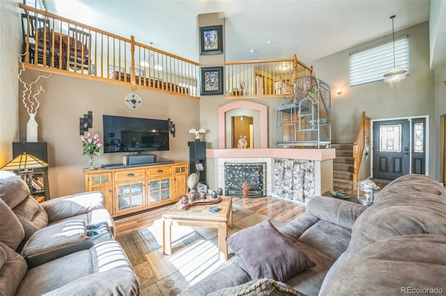living area featuring a high ceiling, stairway, wood finished floors, and a fireplace