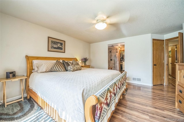 bedroom with wood finished floors, baseboards, a spacious closet, a textured ceiling, and ceiling fan