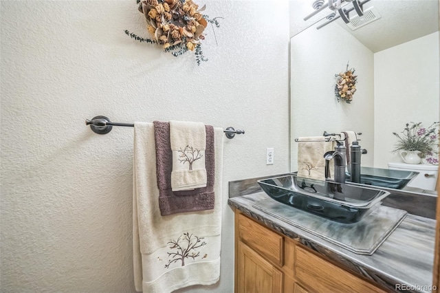 bathroom featuring a textured wall and vanity