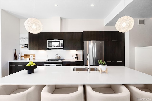 kitchen featuring a kitchen breakfast bar, visible vents, a sink, light countertops, and stainless steel appliances