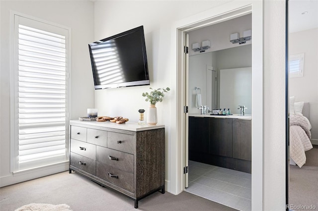 bedroom featuring a sink, light carpet, and ensuite bath