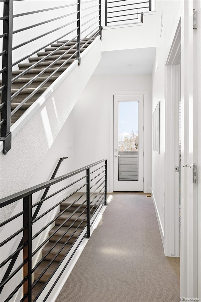interior space with baseboards, carpet flooring, a high ceiling, and an upstairs landing