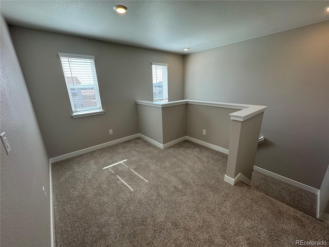 empty room featuring a textured ceiling, baseboards, and carpet floors