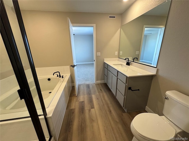 full bath with vanity, a bath, wood finished floors, visible vents, and toilet