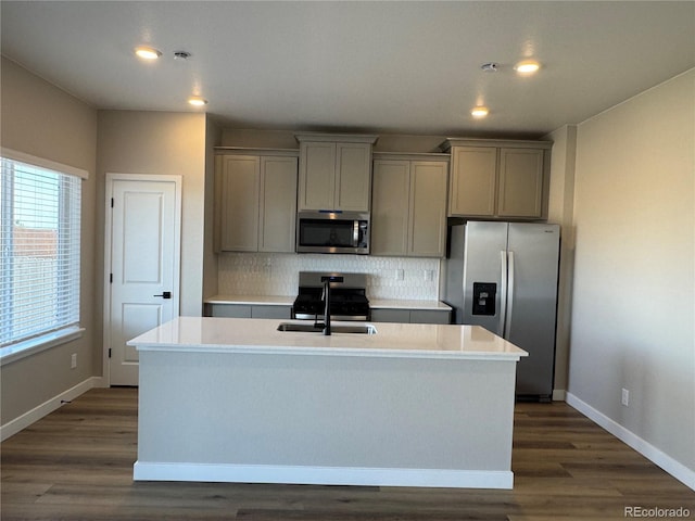 kitchen with a center island with sink, tasteful backsplash, gray cabinets, and appliances with stainless steel finishes