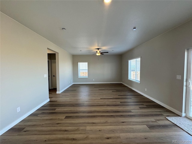 spare room featuring dark wood-type flooring, a healthy amount of sunlight, and baseboards