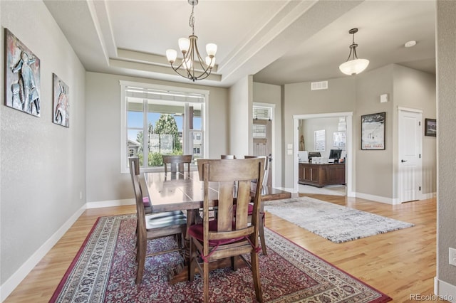 7258 Spanish Bay Dr, Windsor, CO 80550 - dining area featuring light wood-style flooring, a chandelier, and a raised ceiling