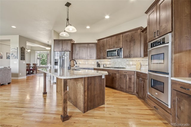 7258 Spanish Bay Dr, Windsor, CO 80550 - kitchen featuring appliances with stainless steel finishes, light wood-style flooring, decorative light fixtures, backsplash, and recessed lighting