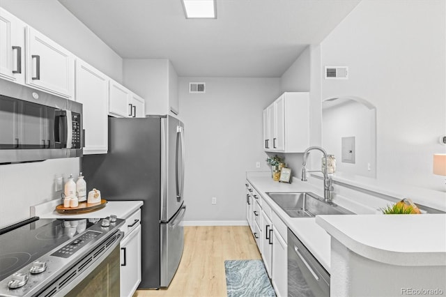 kitchen with white cabinetry, sink, stainless steel appliances, and light hardwood / wood-style flooring