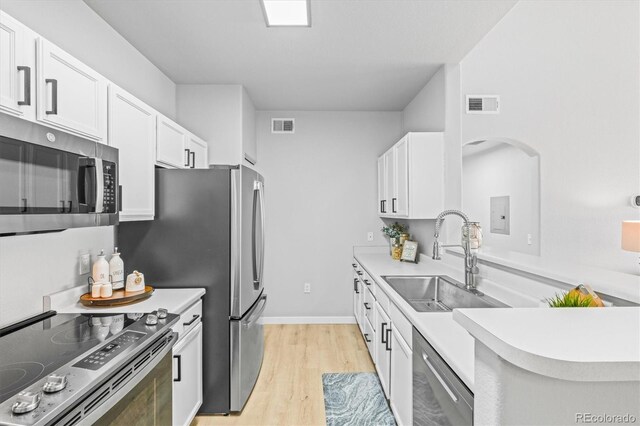 10805 Twenty Mile Rd Unit 307, Parker, CO 80134 - kitchen with stainless steel appliances, white cabinetry, light wood-type flooring, light countertops, and arched walkways