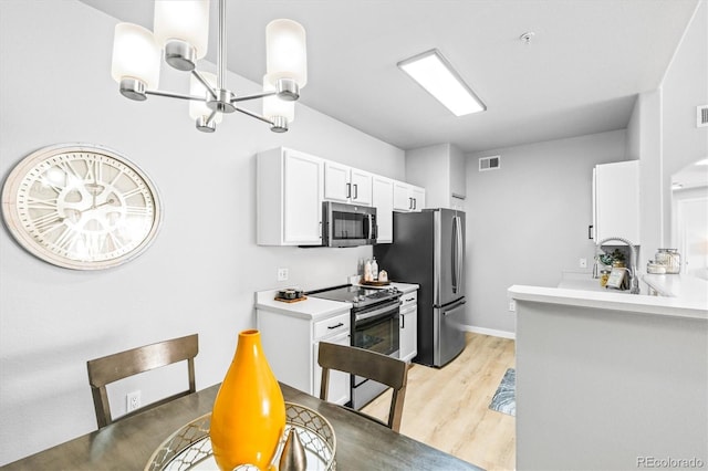 kitchen with white cabinets, a notable chandelier, appliances with stainless steel finishes, and light hardwood / wood-style flooring