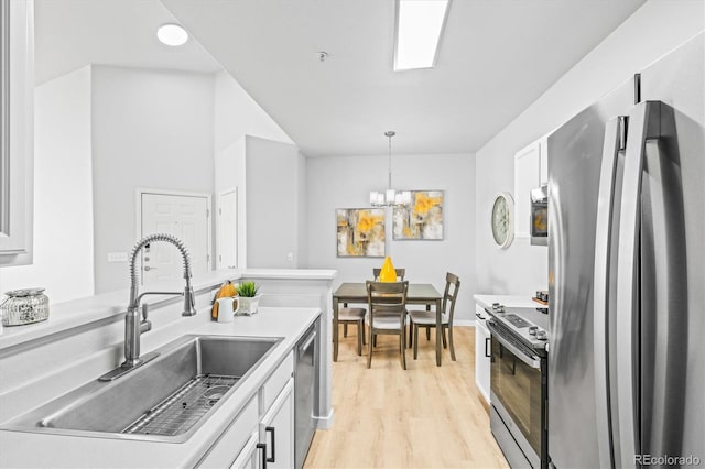 kitchen with sink, stainless steel appliances, light hardwood / wood-style flooring, decorative light fixtures, and white cabinets