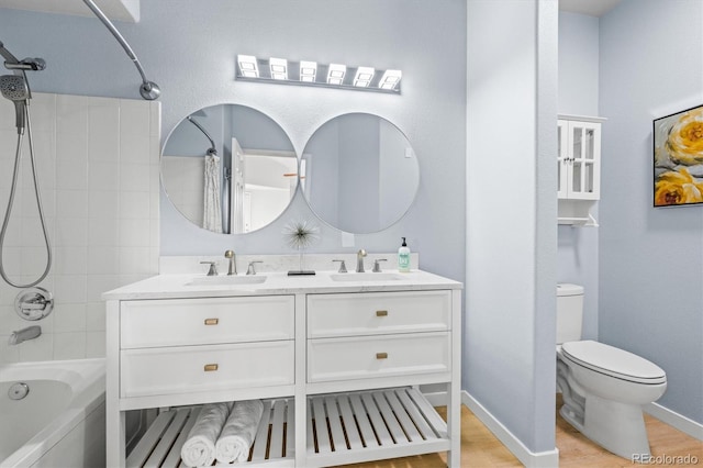 full bathroom with vanity, hardwood / wood-style flooring, toilet, and tiled shower / bath