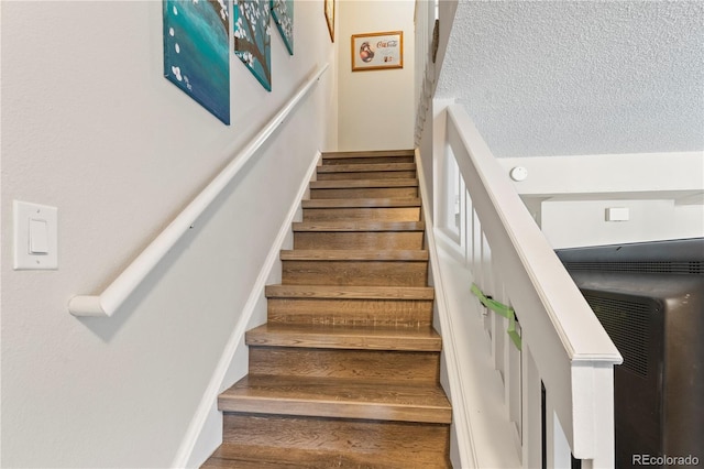 staircase featuring a textured ceiling