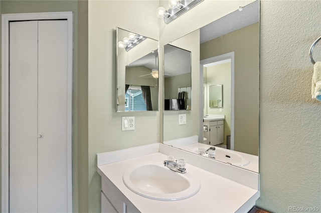 bathroom featuring ceiling fan, vanity, and a textured ceiling