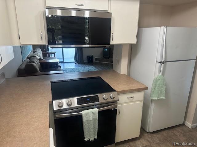 kitchen featuring white cabinets, white refrigerator, and stainless steel range with electric stovetop