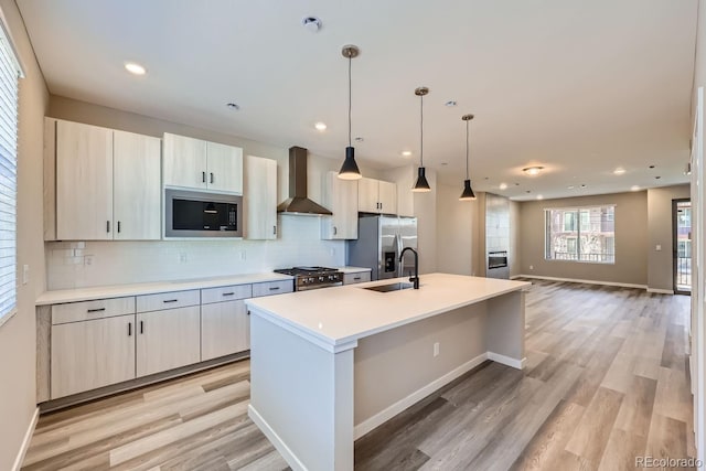 kitchen with pendant lighting, backsplash, a kitchen island with sink, wall chimney exhaust hood, and appliances with stainless steel finishes