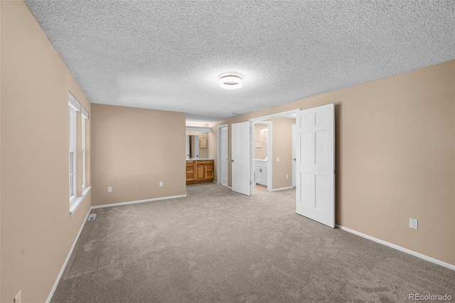 11704 Elk Head Range Rd, Littleton, CO 80127 - unfurnished bedroom featuring light carpet, ensuite bath, and a textured ceiling