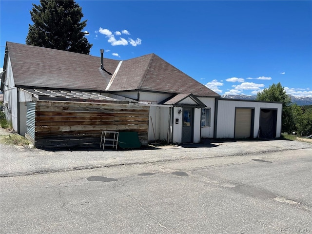 view of front facade with a garage and a shingled roof