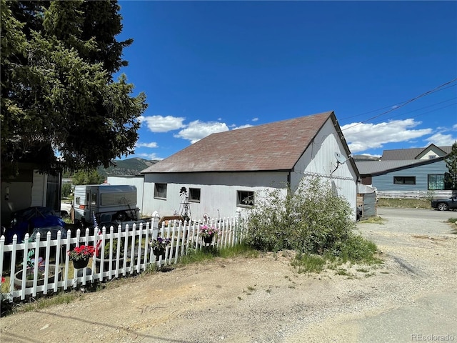 view of home's exterior with a shingled roof and fence