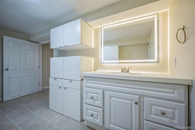 bathroom with a textured wall, tile patterned flooring, and vanity