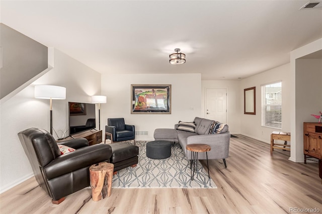 living area featuring visible vents, light wood-style flooring, and baseboards
