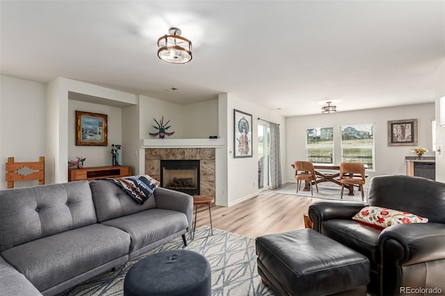 living area featuring baseboards, light wood-type flooring, and a fireplace