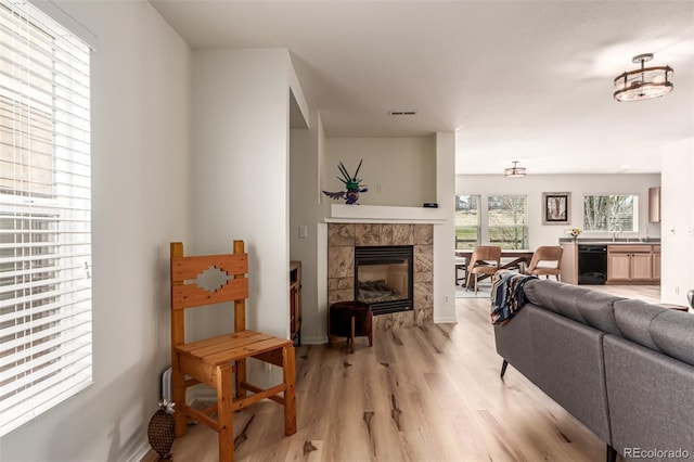 living room featuring a fireplace, visible vents, and light wood-type flooring