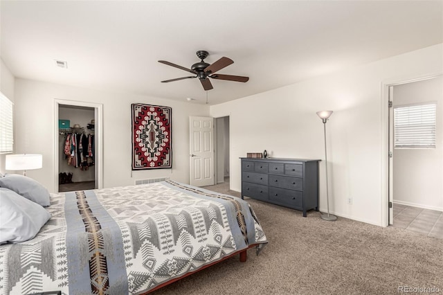 bedroom featuring visible vents, a closet, a spacious closet, a ceiling fan, and light colored carpet