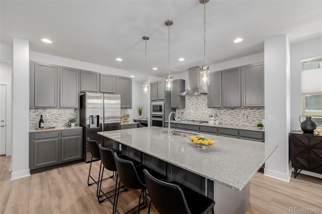 13736 Umatilla Ln, Broomfield, CO 80023 - kitchen with wall chimney range hood, stainless steel appliances, gray cabinetry, light wood-type flooring, and decorative backsplash