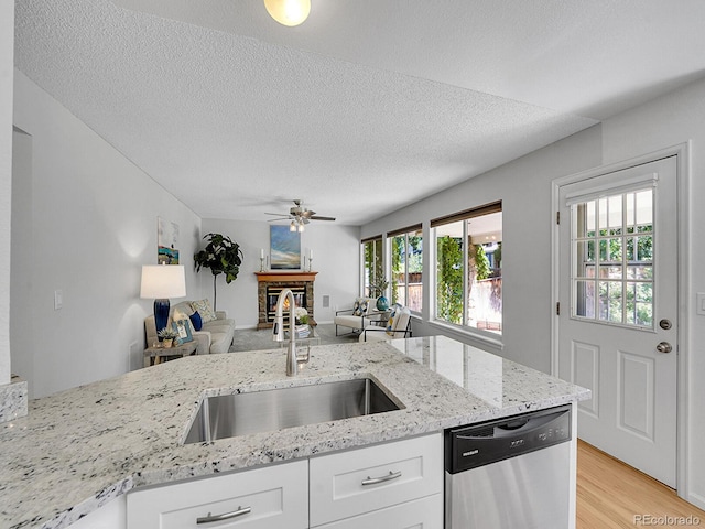 3661 Seramonte Dr, Highlands Ranch, CO 80129 - kitchen featuring stainless steel dishwasher, a ceiling fan, open floor plan, light wood-style flooring, and white cabinetry