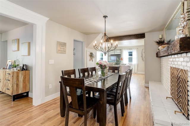 5332 W Roxbury Pl, Littleton, CO 80128 - dining area with light wood-style floors, a chandelier, baseboards, and a brick fireplace