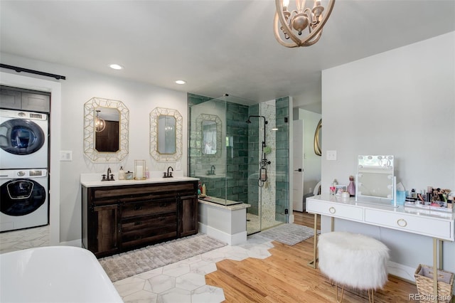 5332 W Roxbury Pl, Littleton, CO 80128 - full bath featuring stacked washer and clothes dryer, a shower stall, double vanity, a soaking tub, and a chandelier